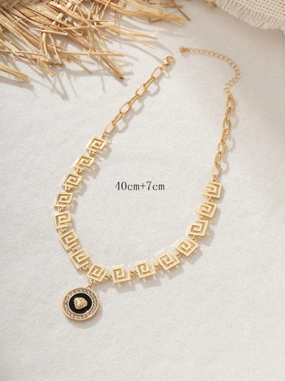 Gold necklace with a black pendant on a light background
