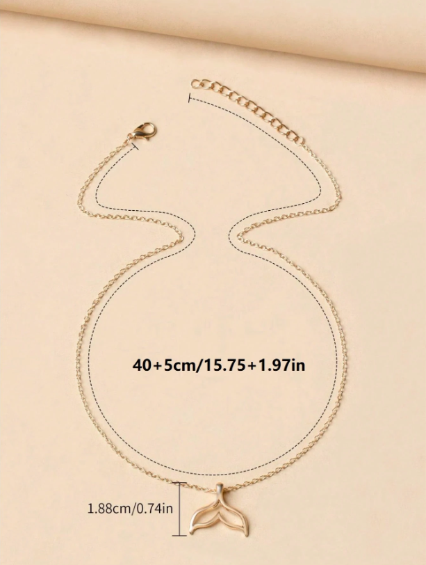 Gold necklace with a whale tail pendant on a beige background, showing measurements.