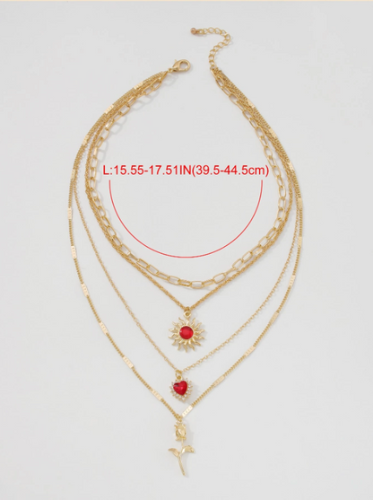 Gold necklace with red heart and sunflower pendants on a light gray background