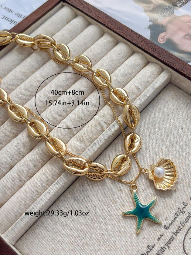Gold bracelet with shell and starfish charms on a textured surface