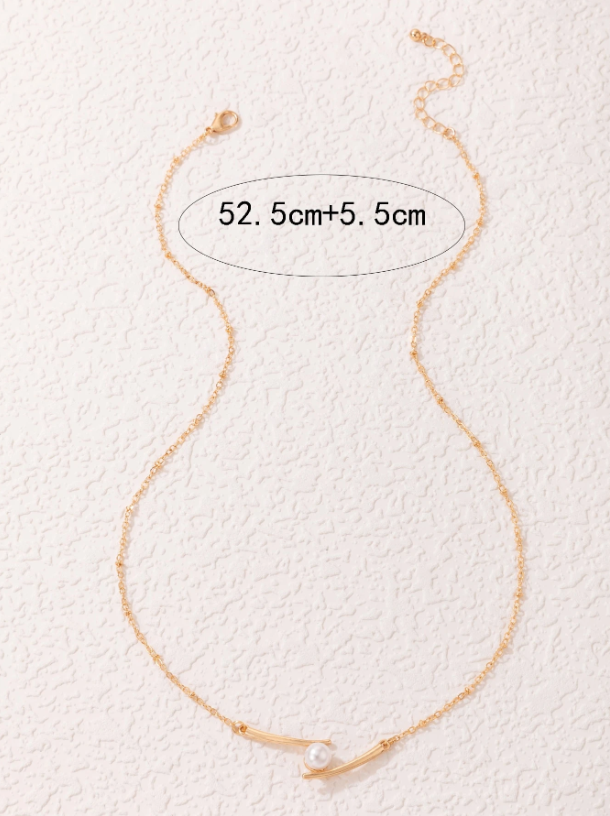 Gold necklace with a pearl on a textured white background