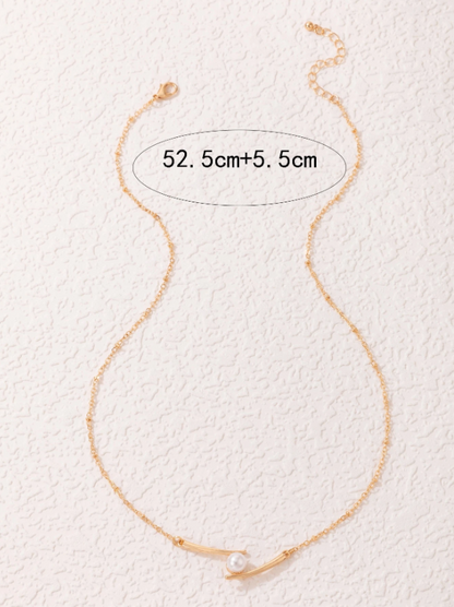 Gold necklace with a pearl on a textured white background