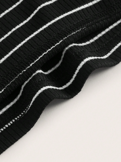Close-up of a black ribbed knit fabric with thin white vertical stripes, draped diagonally on a light neutral background.