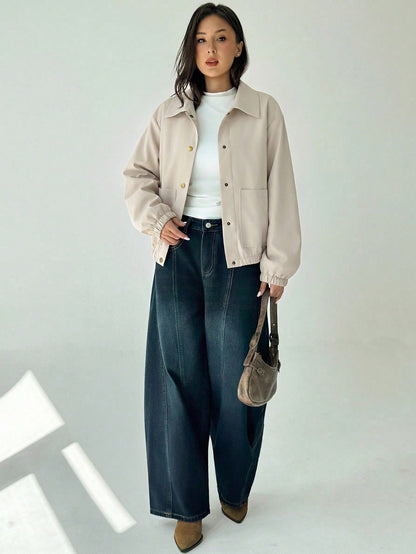 A woman wearing a Beige casual jacket with a contrasting brown lapel collar, drop shoulders, and front pockets paired with a white tee and dark jeans