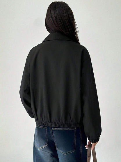 A woman wearing a Black casual jacket with a contrasting brown lapel collar, drop shoulders, and front pockets paired with a white tee and dark jeans