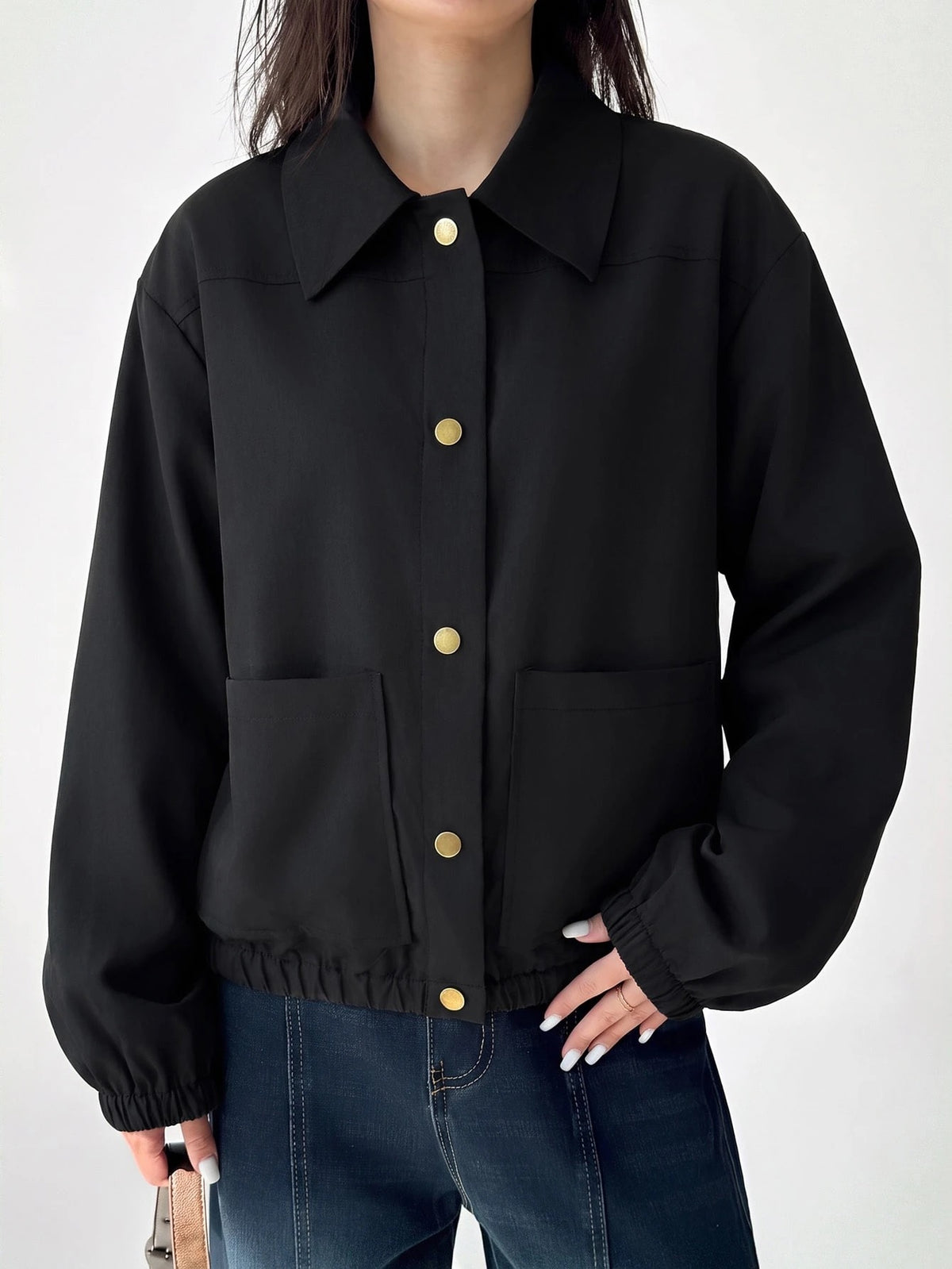 A woman wearing a Black casual jacket with a contrasting brown lapel collar, drop shoulders, and front pockets paired with a white tee and dark jeans