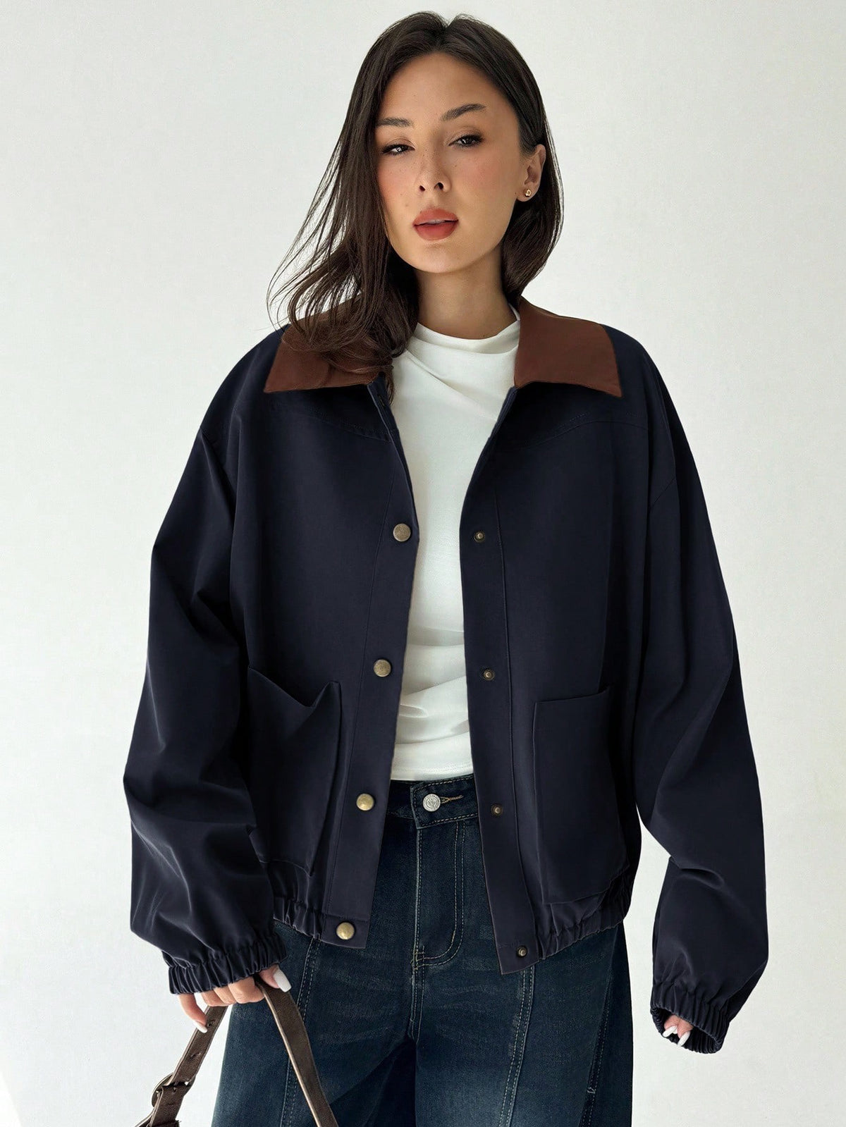 A woman wearing a Royal Blue casual jacket with a contrasting brown lapel collar, drop shoulders, and front pockets paired with a white tee and dark jeans