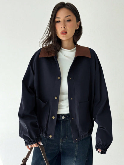 A woman wearing a Royal Blue casual jacket with a contrasting brown lapel collar, drop shoulders, and front pockets paired with a white tee and dark jeans