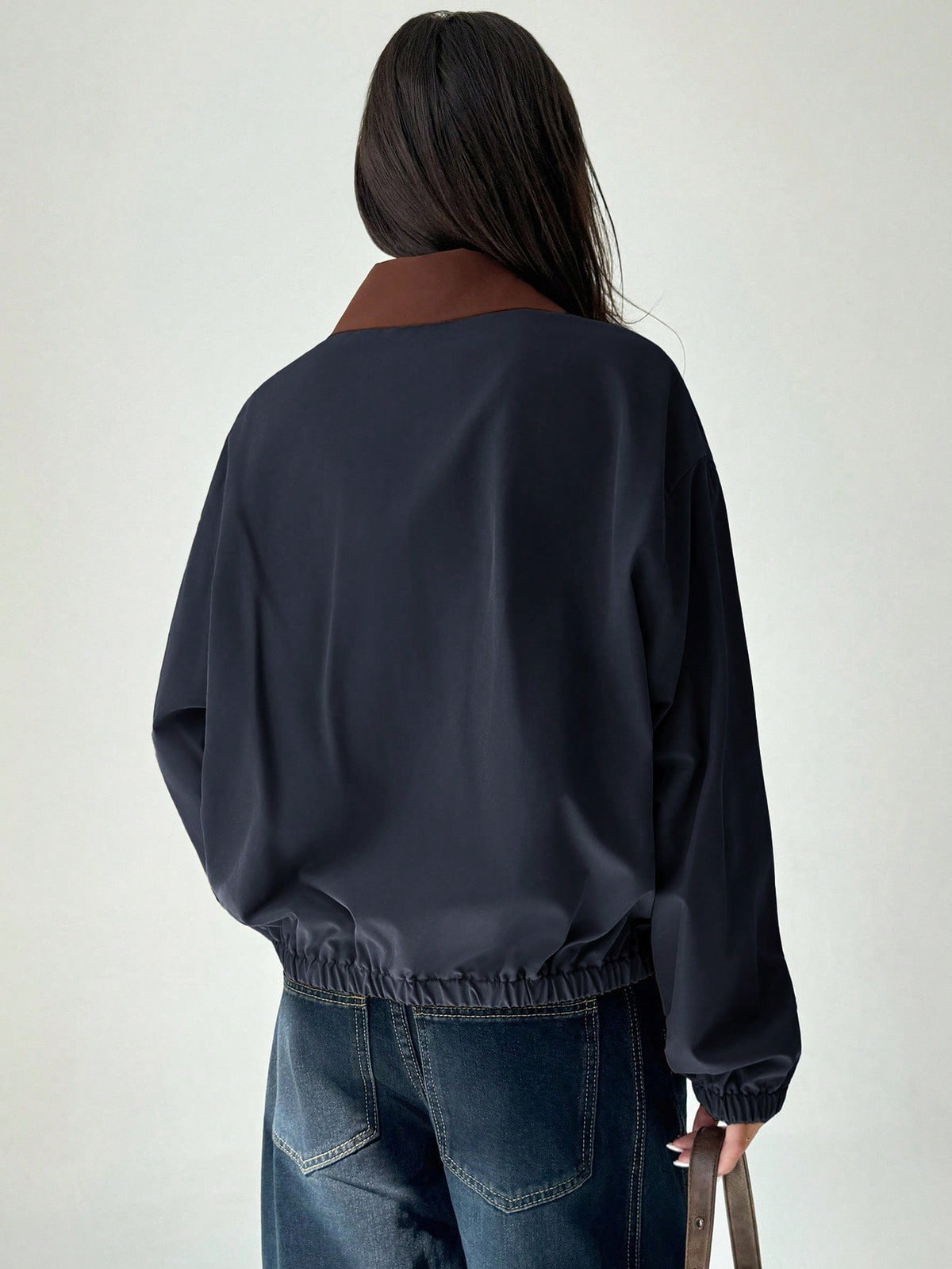 A woman wearing a Royal Blue casual jacket with a contrasting brown lapel collar, drop shoulders, and front pockets paired with a white tee and dark jeans