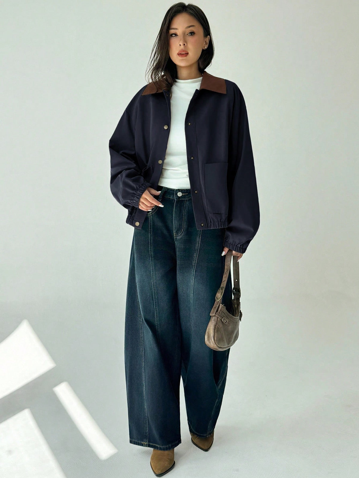 A woman wearing a Royal Blue casual jacket with a contrasting brown lapel collar, drop shoulders, and front pockets paired with a white tee and dark jeans