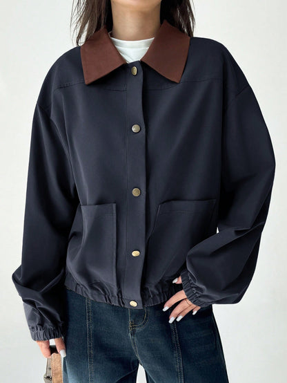 A woman wearing a Royal Blue casual jacket with a contrasting brown lapel collar, drop shoulders, and front pockets paired with a white tee and dark jeans