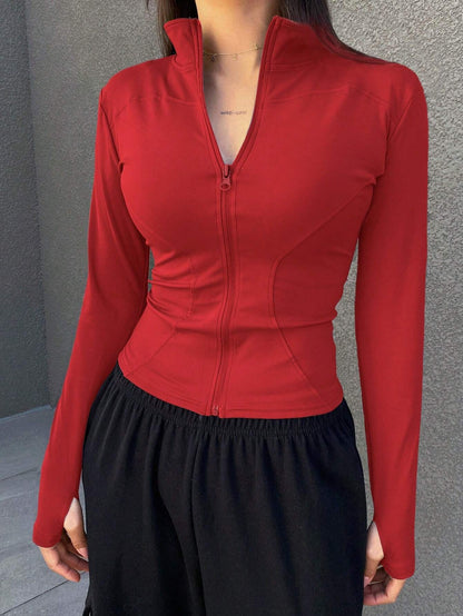 A woman wearing a red long-sleeve zip-up jacket with thumb holes and a high mock neck paired with black pants