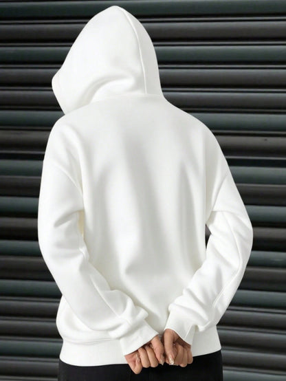 A woman wearing a white fleece balaclava zip-up hoodie featuring an integrated face mask and front pockets while standing indoors