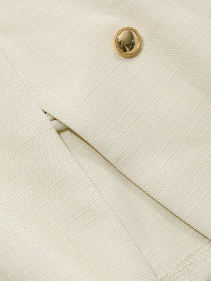 A woman wearing an apricot short jacket featuring gold button accents and long sleeves paired with high-waisted black trousers