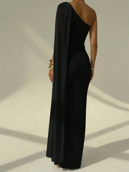 A woman wearing an elegant Black  one-shoulder ruched mermaid long dress with a dramatic flutter cloak sleeve