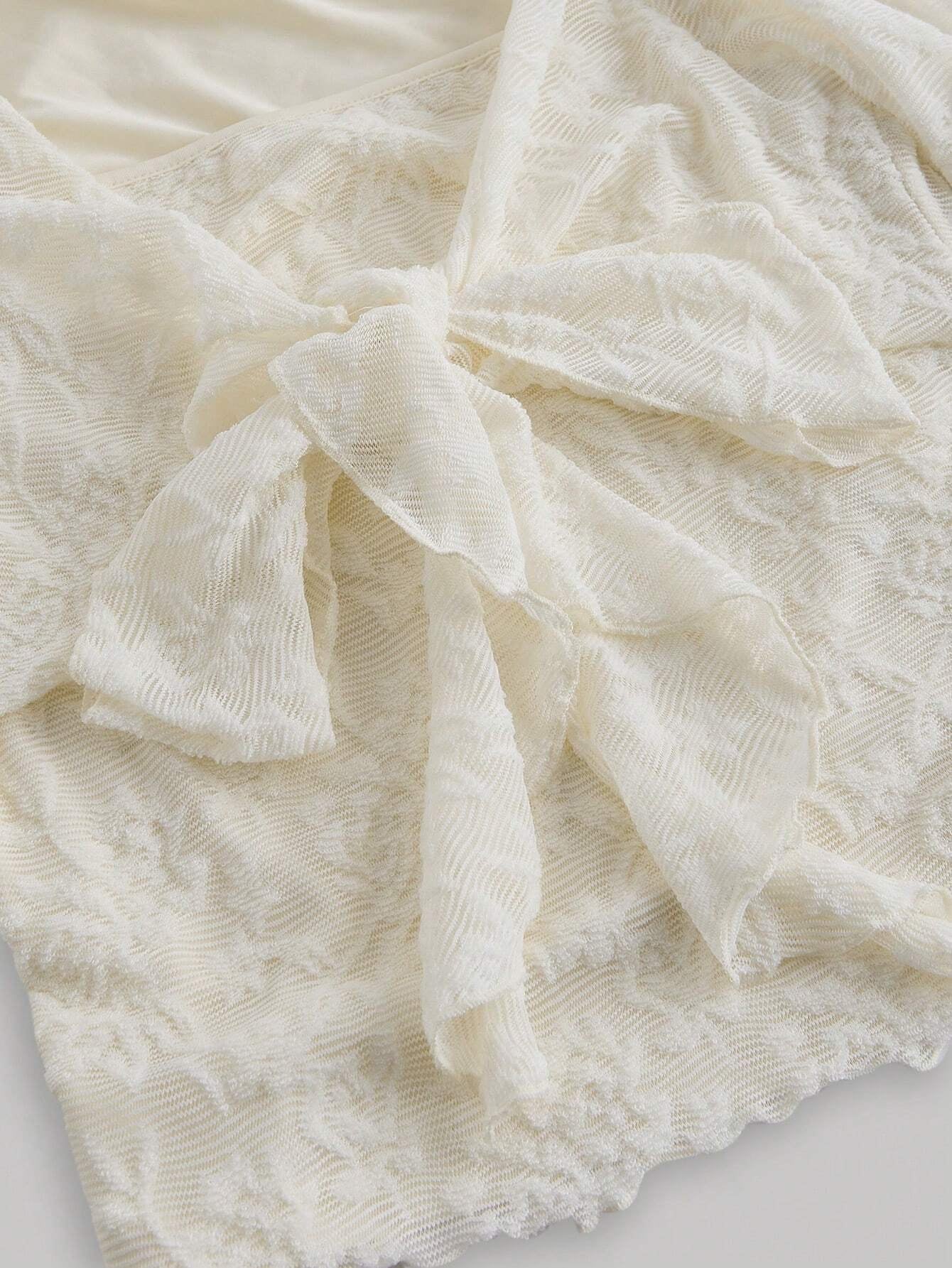 Apricot sheer floral lace tie-front long flare sleeve top laid flat against a neutral background