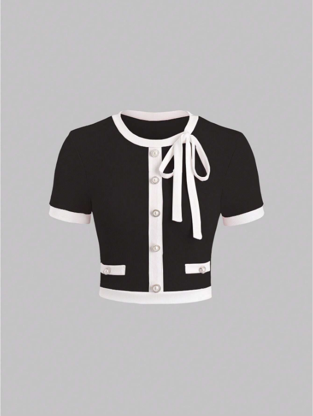 Black cardigan with white trim and bow on a gray background