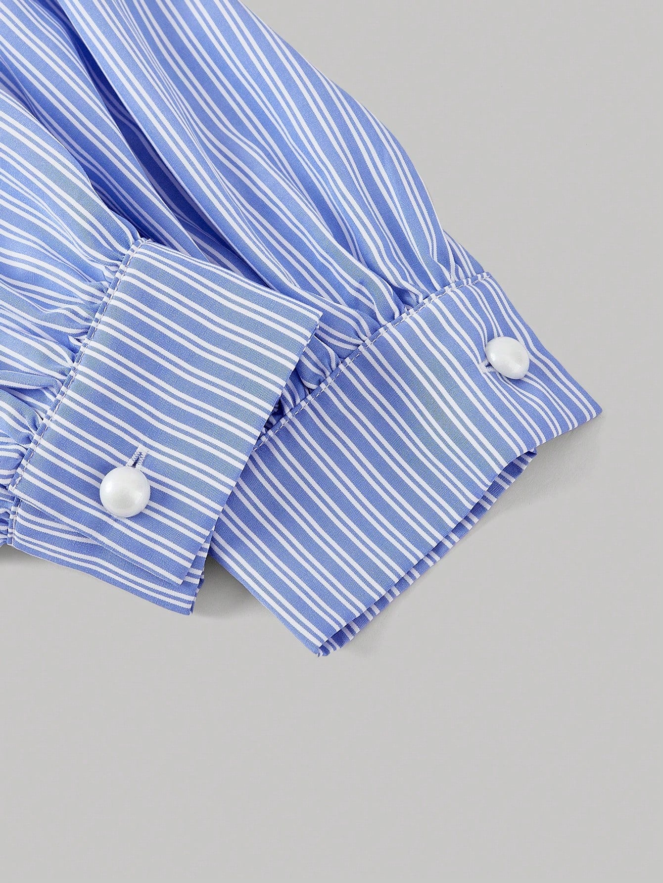 Blue and white striped long-sleeve peplum blouse with a lace-trim V-neck, button-front closure, and lantern sleeves against a neutral background.