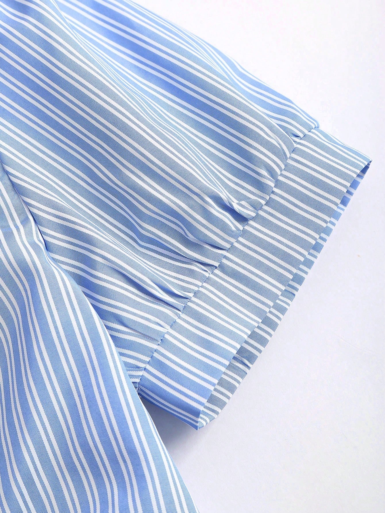 Blue and white striped short-sleeve polo collar peplum blouse with a wrap-effect ruched waist laid flat against a neutral background