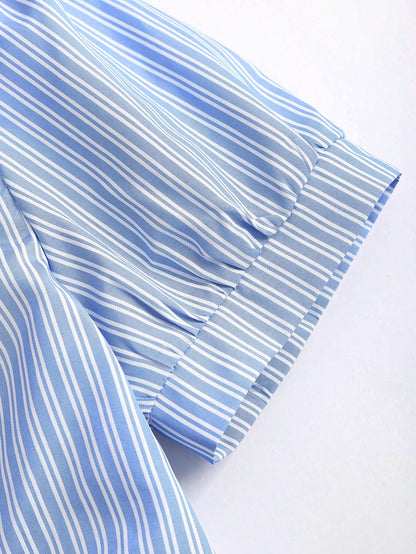 Blue and white striped short-sleeve polo collar peplum blouse with a wrap-effect ruched waist laid flat against a neutral background