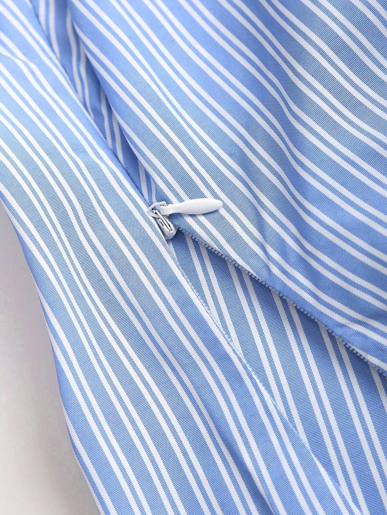Blue and white striped short-sleeve polo collar peplum blouse with a wrap-effect ruched waist laid flat against a neutral background