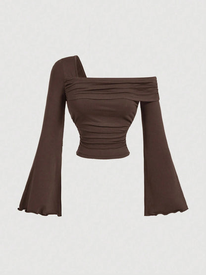 Brown asymmetric neckline ruched long flare sleeve top laid flat against a neutral background