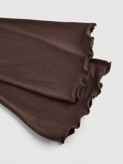Brown asymmetric neckline ruched long flare sleeve top laid flat against a neutral background