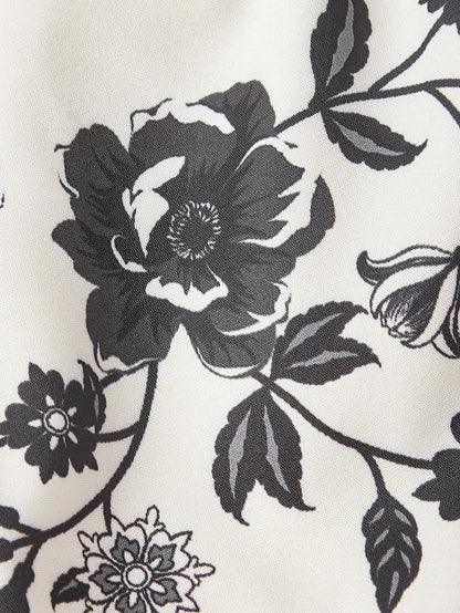 Elegant white A-line midi dress with black and white floral border print and spaghetti straps2