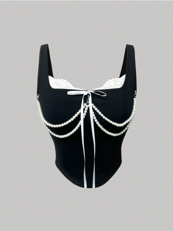 Black swimsuit with white lace and chain details on a gray background