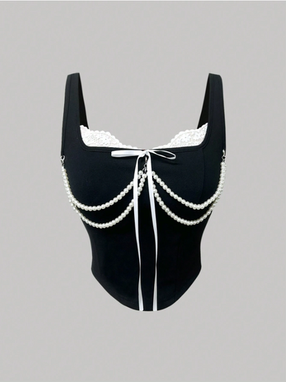 Black swimsuit with white lace and chain details on a gray background