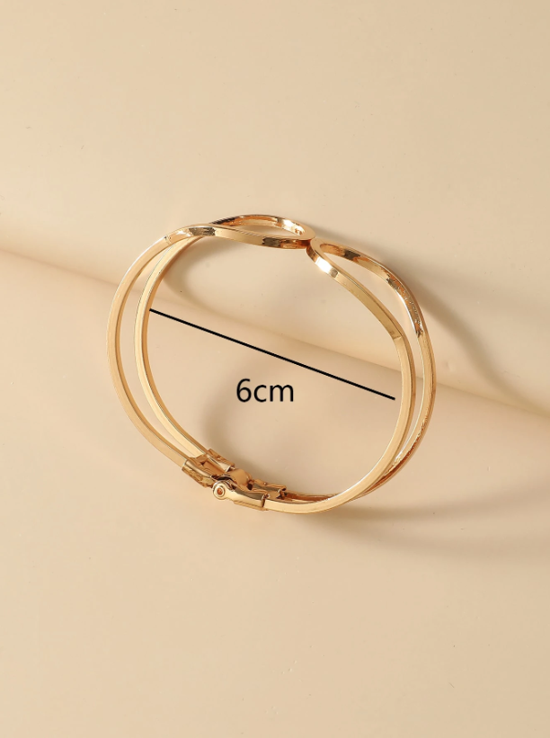 Gold bracelet on a beige background with measurement label
