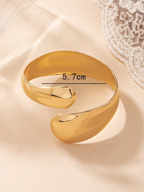 Gold bracelet on a beige fabric background with measurement label