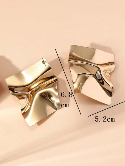 Gold earrings with measurements on a beige background