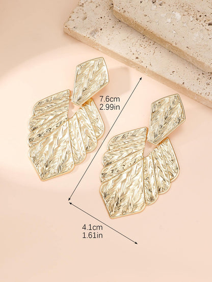 Gold leaf-shaped earrings with measurements on a beige background