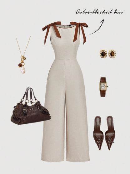 Khaki wide-leg sleeveless jumpsuit featuring contrast brown shoulder bow ties and trim laid flat against a neutral background