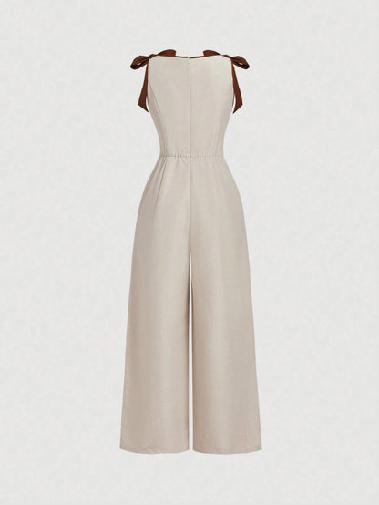 Khaki wide-leg sleeveless jumpsuit featuring contrast brown shoulder bow ties and trim laid flat against a neutral background