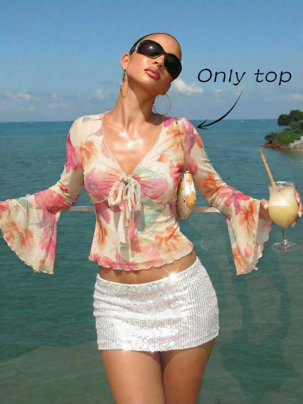 Pink and green floral print long-sleeve flare blouse with a V-neck and twist-front tie detail laid flat against a neutral background