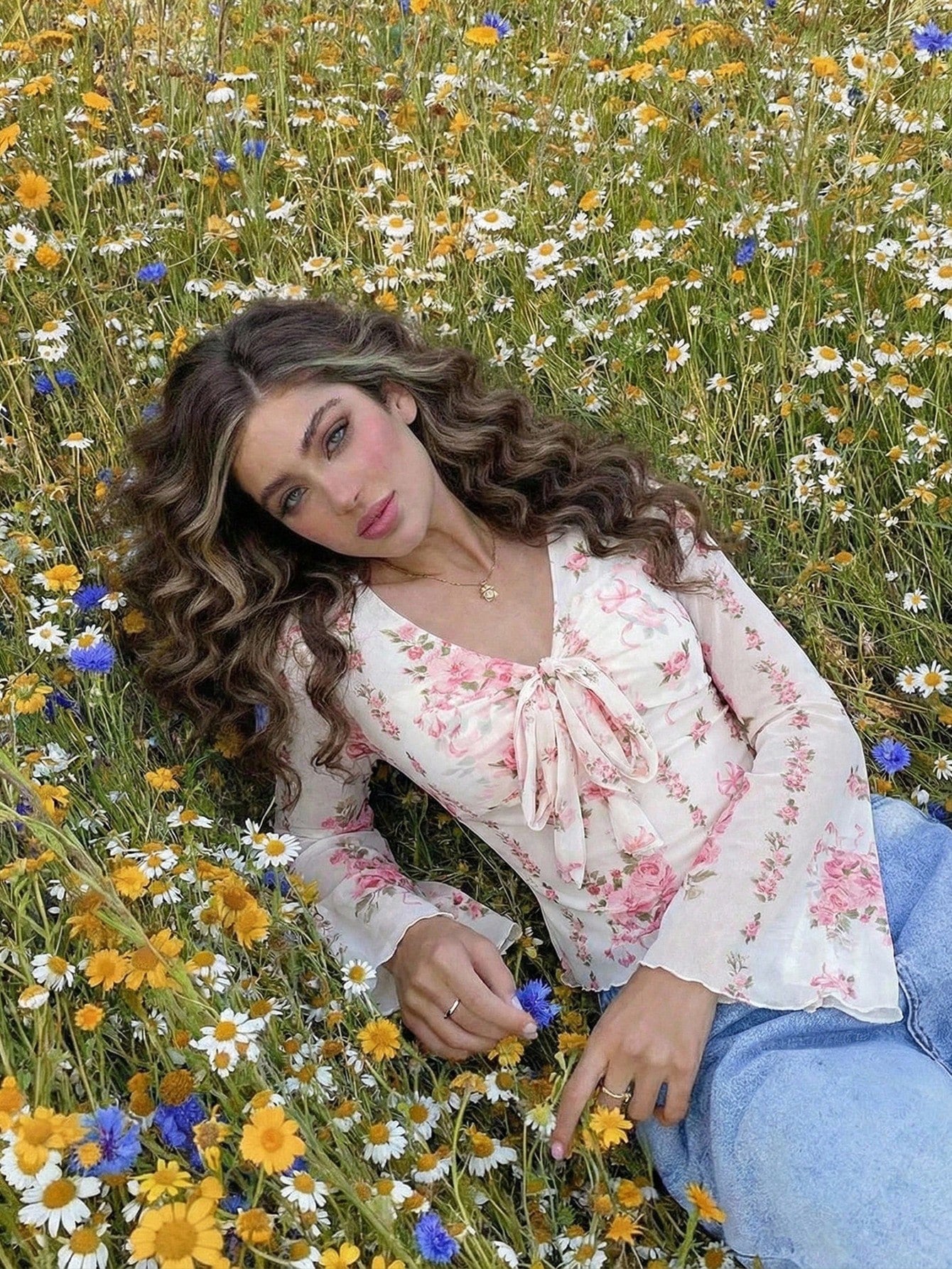 Pink and white floral print tie-front flare sleeve top laid flat against a neutral background
