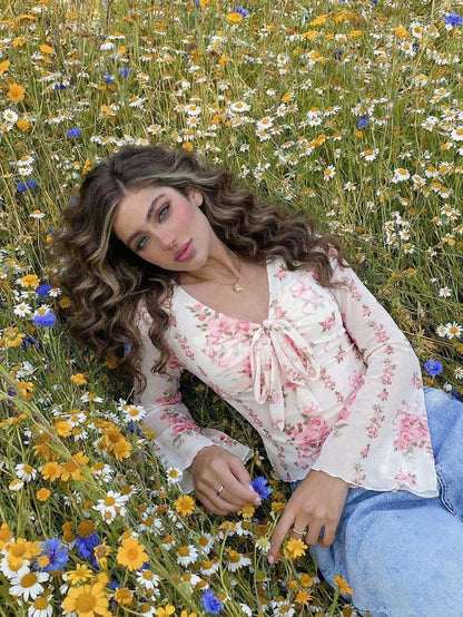Pink and white floral print tie-front flare sleeve top laid flat against a neutral background