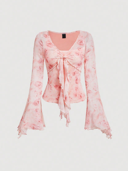 Pink floral print sheer mesh long-sleeve top with a tie-front closure, V-neck, and dramatic bell sleeves on a neutral background.