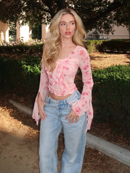 Pink floral print sheer mesh long-sleeve top with a tie-front closure, V-neck, and dramatic bell sleeves on a neutral background.