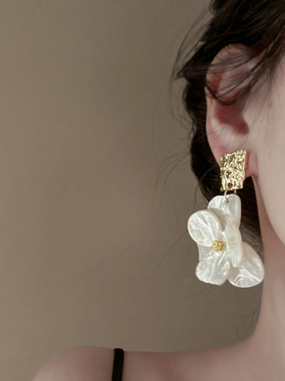 Close-up of a person wearing a floral earring with a beige background