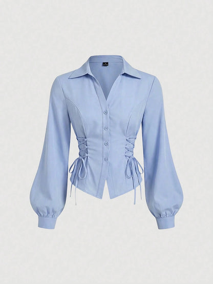 Solid color blue button-down shirt with lapel collar, lantern sleeves, and waist lace-up corset ties laid flat