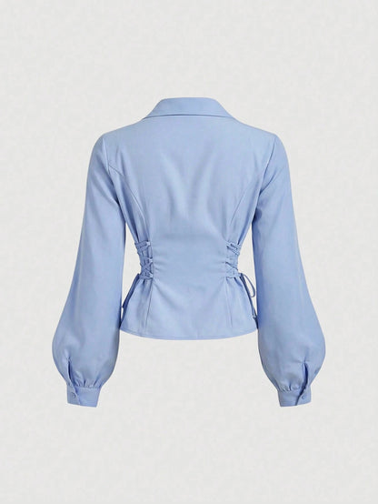 Solid color blue button-down shirt with lapel collar, lantern sleeves, and waist lace-up corset ties laid flat