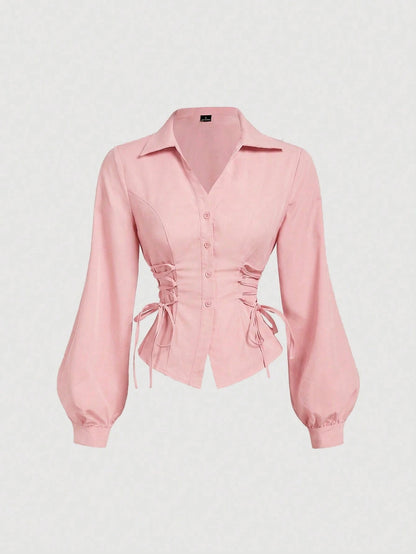 Solid color pink button-down shirt with lapel collar, lantern sleeves, and waist lace-up corset ties laid flat