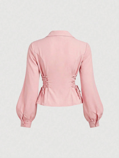 Solid color pink button-down shirt with lapel collar, lantern sleeves, and waist lace-up corset ties laid flat