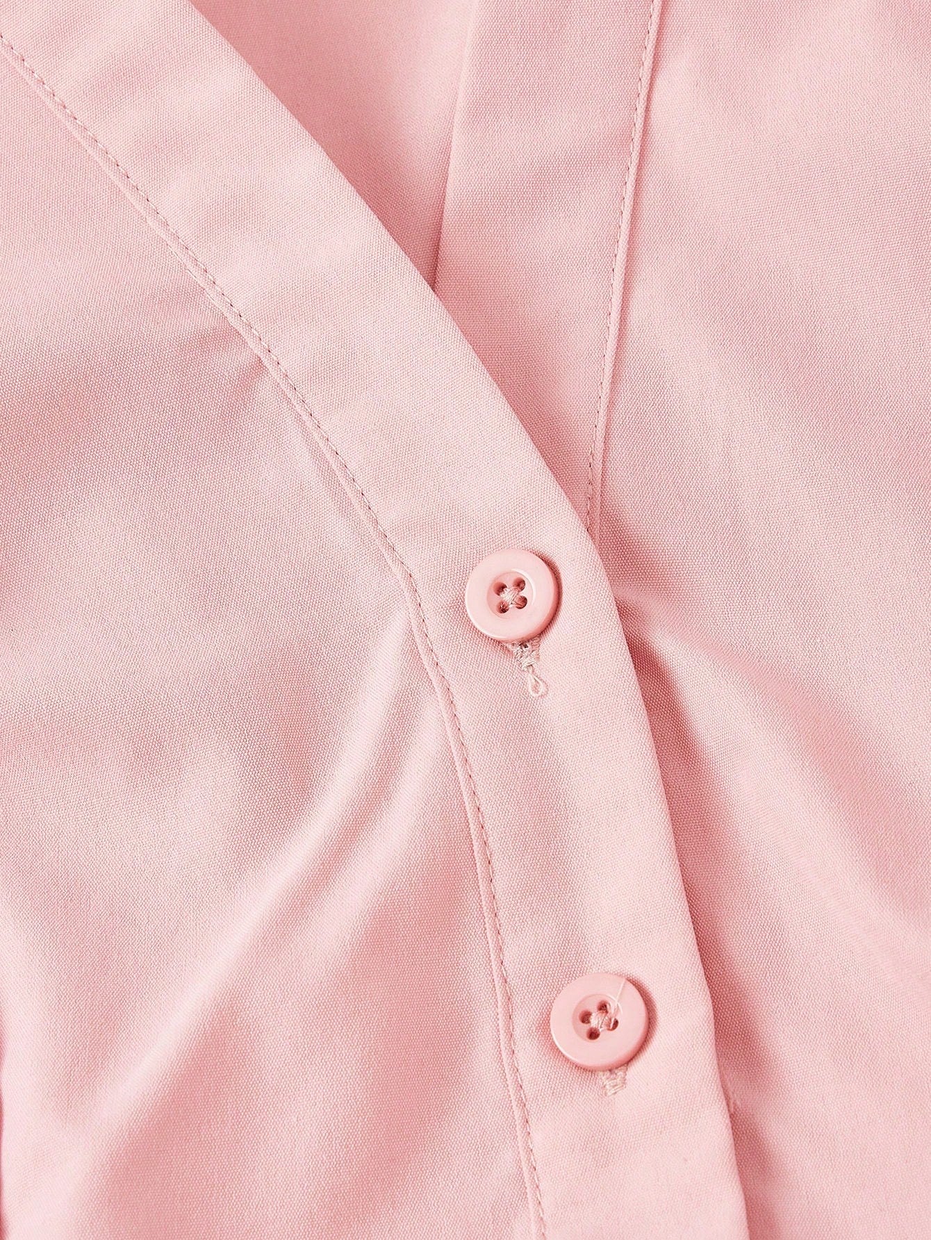Solid color pink button-down shirt with lapel collar, lantern sleeves, and waist lace-up corset ties laid flat