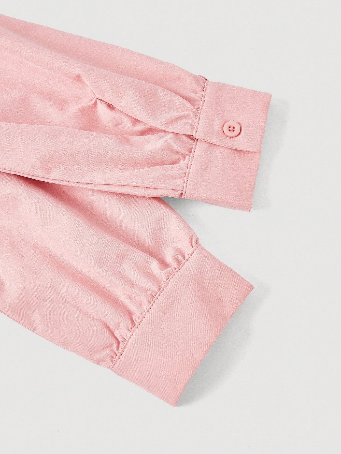 Solid color pink button-down shirt with lapel collar, lantern sleeves, and waist lace-up corset ties laid flat