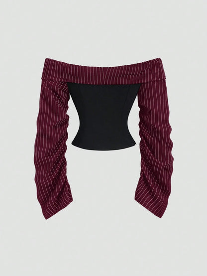 Two-tone off-shoulder black top with striped maroon sleeves and an attached necktie detail laid flat against a neutral background