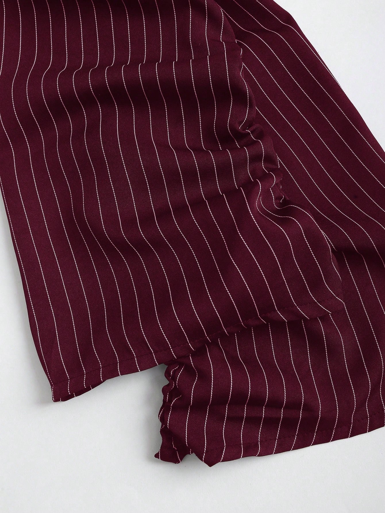 Two-tone off-shoulder black top with striped maroon sleeves and an attached necktie detail laid flat against a neutral background